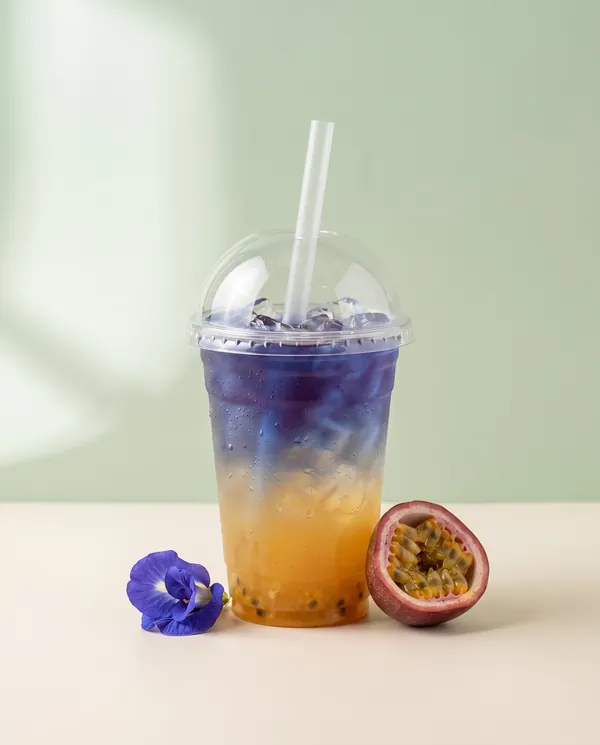 Butterfly pea tea layered over passion fruit juice with a butterfly pea flower